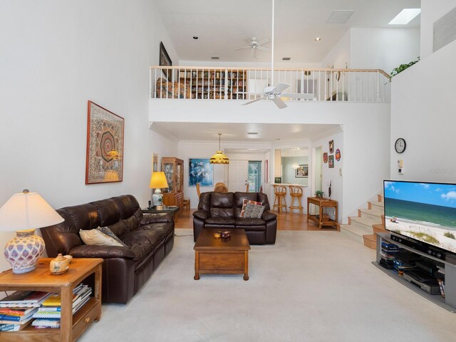 living room with light carpet, a high ceiling, crown molding, and ceiling fan