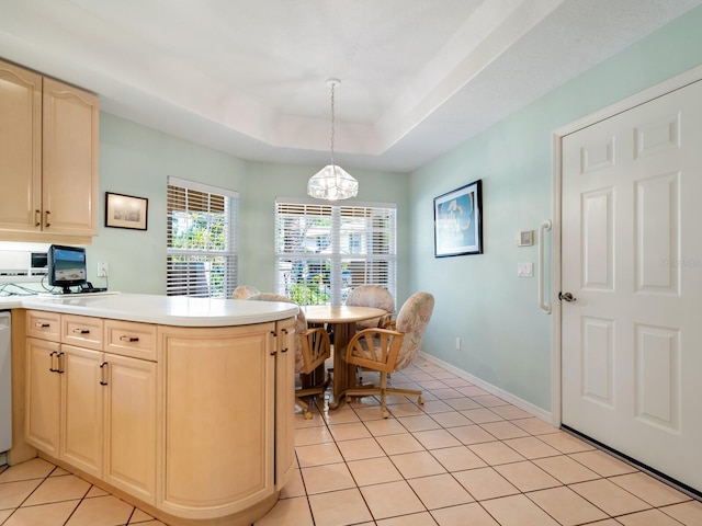 kitchen with pendant lighting, light brown cabinetry, white dishwasher, light tile floors, and a raised ceiling