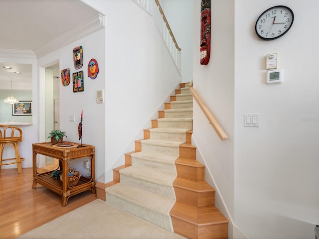 stairway with hardwood / wood-style floors and ornamental molding