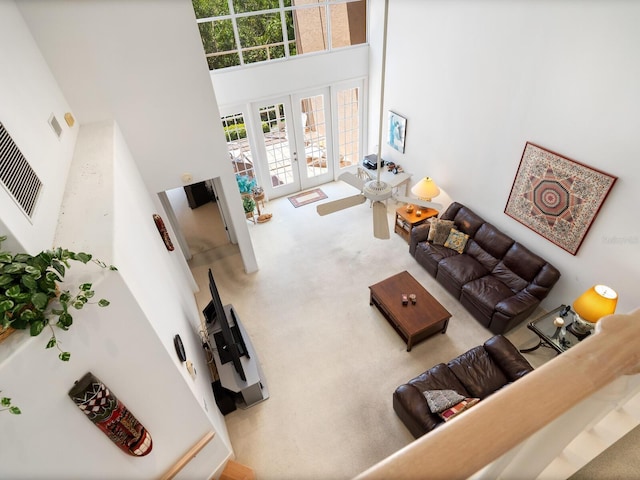 living room with a high ceiling, carpet flooring, and french doors