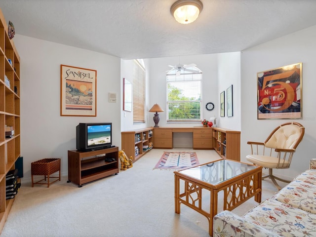 sitting room featuring ceiling fan, carpet floors, and a textured ceiling