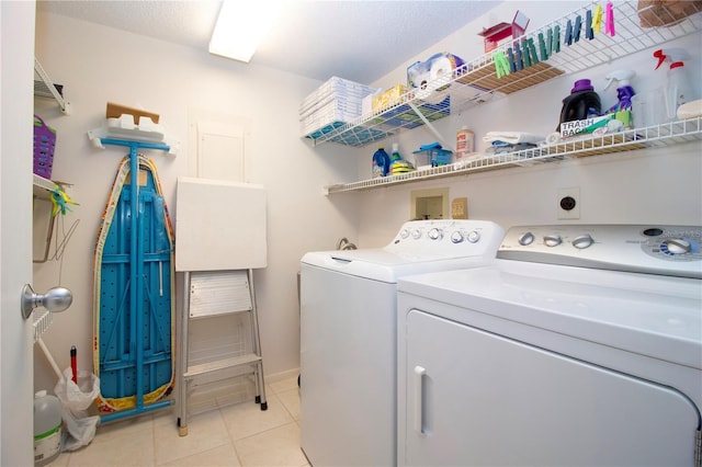 clothes washing area featuring washer and dryer, a textured ceiling, and light tile patterned floors