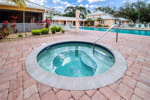 view of pool featuring a sunroom, a patio, and an in ground hot tub