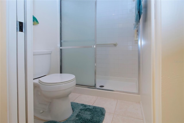 bathroom featuring toilet, a shower with door, and tile patterned floors