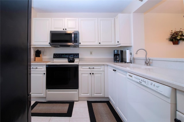 kitchen with dishwasher, range with electric cooktop, white cabinets, light tile patterned flooring, and sink