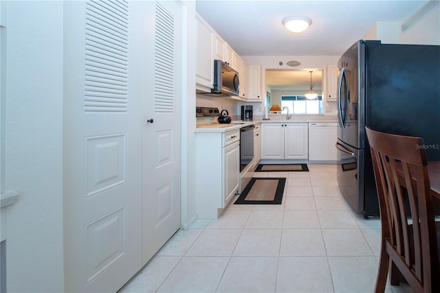 kitchen featuring decorative light fixtures, white appliances, sink, and light tile patterned floors