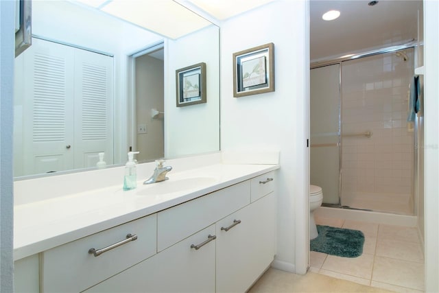 bathroom with toilet, tile patterned flooring, a shower with shower door, and vanity