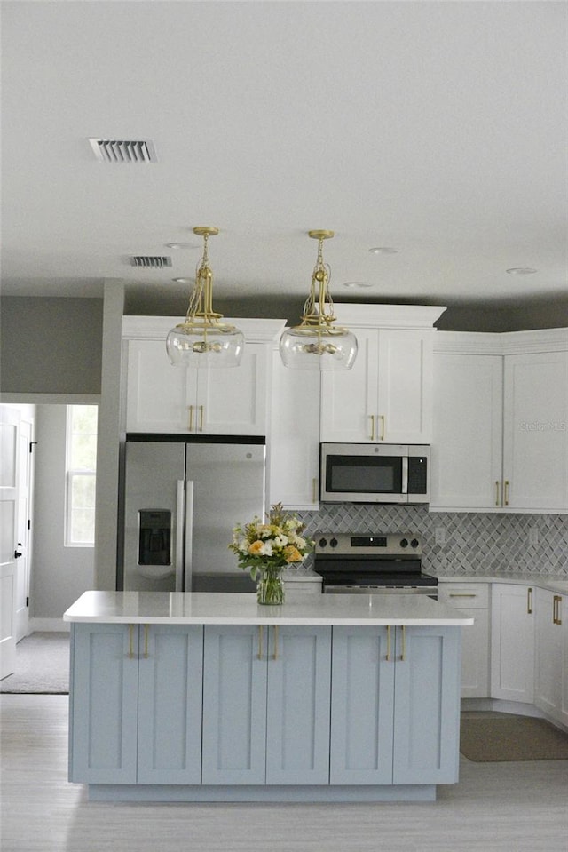 kitchen featuring white cabinetry, light hardwood / wood-style flooring, tasteful backsplash, decorative light fixtures, and stainless steel appliances