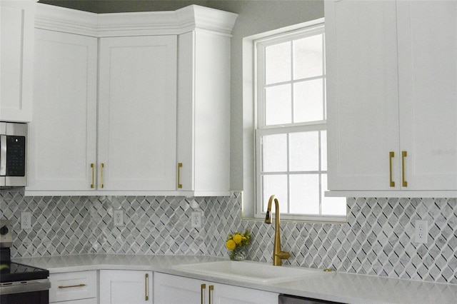 kitchen featuring tasteful backsplash, sink, stainless steel appliances, and white cabinets