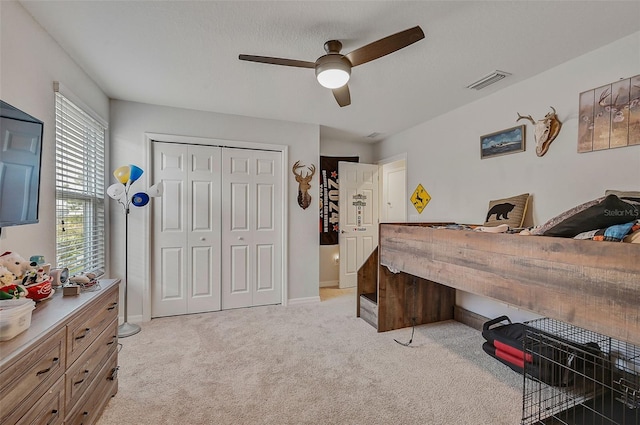 bedroom with light colored carpet, ceiling fan, and a closet