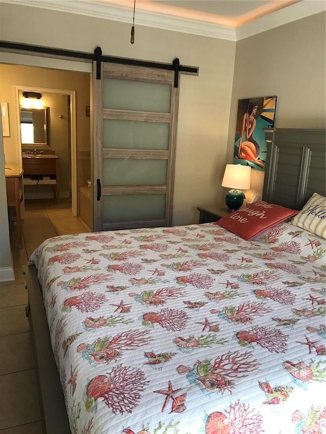 bedroom with ornamental molding, tile floors, and a barn door