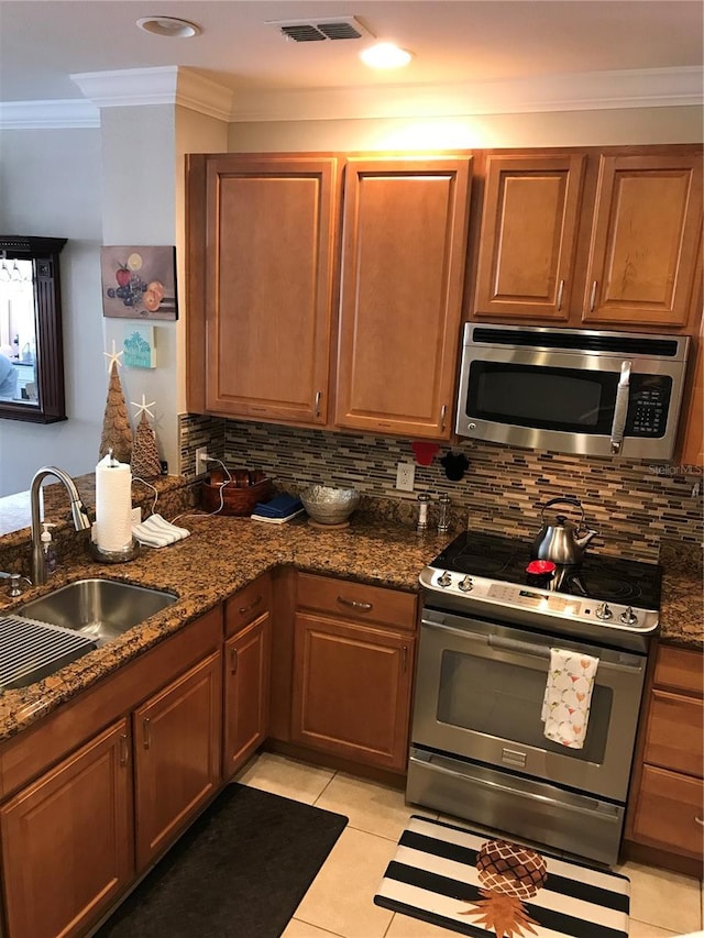 kitchen with tasteful backsplash, stainless steel appliances, sink, and light tile floors