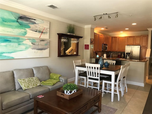 living room featuring rail lighting, sink, crown molding, and light tile flooring