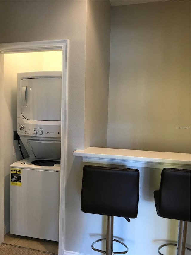 laundry area featuring stacked washer / dryer and tile floors