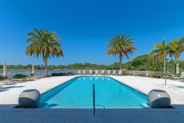 community pool featuring a water view, a patio, and fence