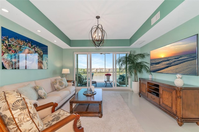 living room featuring a raised ceiling and a notable chandelier