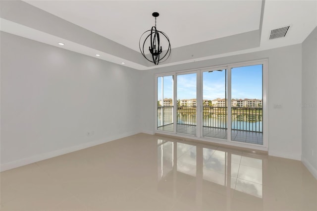 tiled spare room featuring a water view and an inviting chandelier