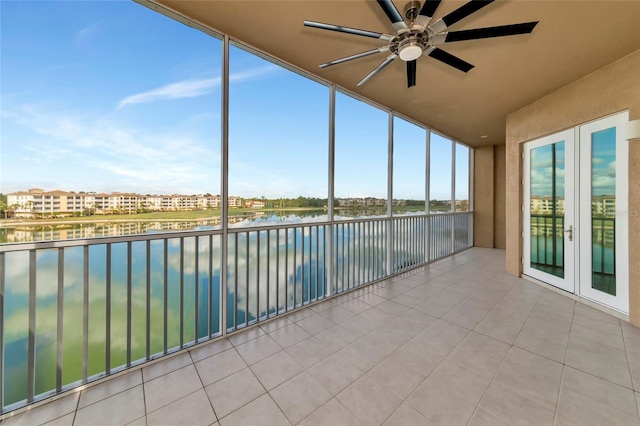 unfurnished sunroom featuring ceiling fan, a water view, and french doors