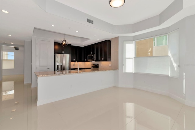 kitchen with decorative backsplash, light stone countertops, light tile patterned floors, kitchen peninsula, and stainless steel appliances