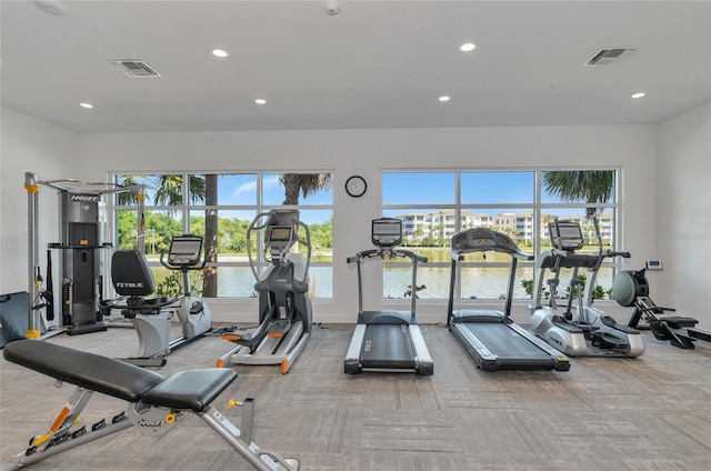 workout area with carpet flooring and a water view