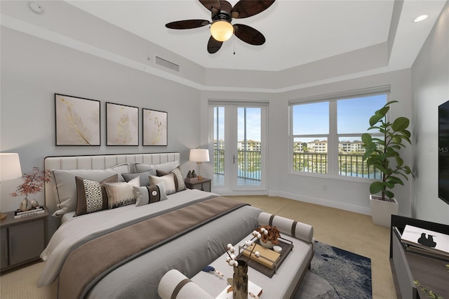 bedroom with light carpet, baseboards, visible vents, and a raised ceiling