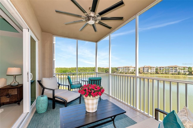 sunroom / solarium with a ceiling fan and a water view