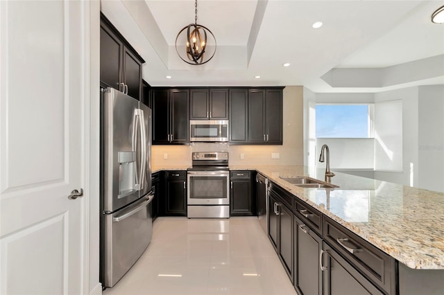 kitchen with tasteful backsplash, a raised ceiling, a peninsula, stainless steel appliances, and a sink