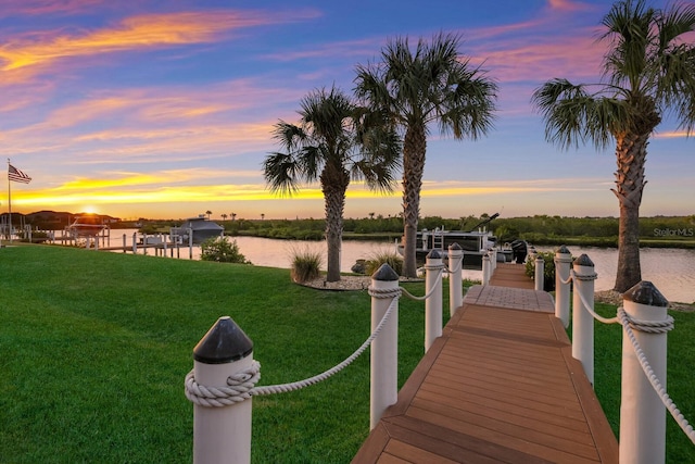 view of dock featuring a lawn and a water view