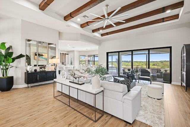 living room featuring ceiling fan, light hardwood / wood-style floors, a healthy amount of sunlight, and beamed ceiling