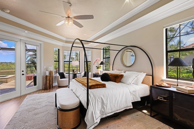 bedroom with access to outside, crown molding, a raised ceiling, ceiling fan, and light hardwood / wood-style flooring