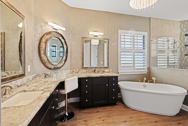 bathroom with a chandelier, vanity, hardwood / wood-style floors, and a bathing tub