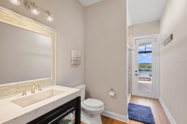 bathroom featuring hardwood / wood-style floors, vanity, an enclosed shower, toilet, and decorative backsplash