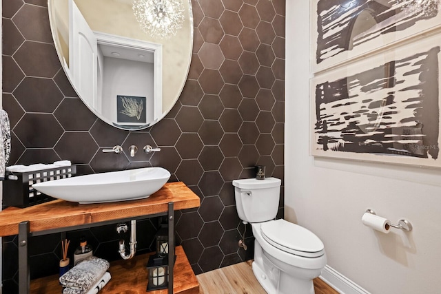 bathroom featuring sink, tasteful backsplash, an inviting chandelier, toilet, and tile walls