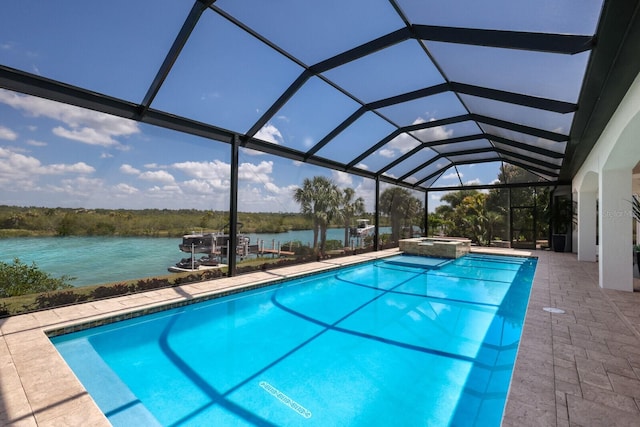 view of pool featuring glass enclosure, a water view, a patio, and an in ground hot tub