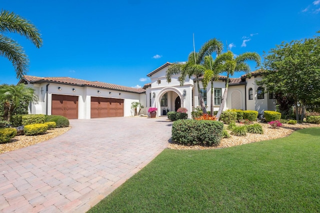 mediterranean / spanish-style house featuring a garage and a front lawn