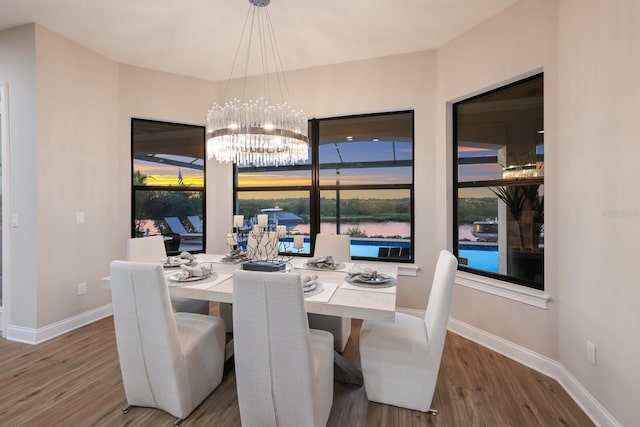 dining space featuring wood-type flooring, a healthy amount of sunlight, and a notable chandelier