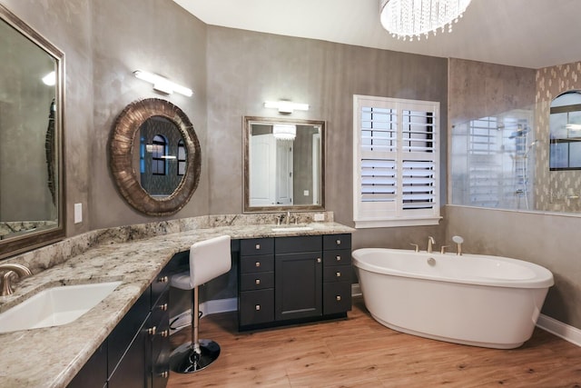 bathroom with wood-type flooring, a tub to relax in, a chandelier, and vanity