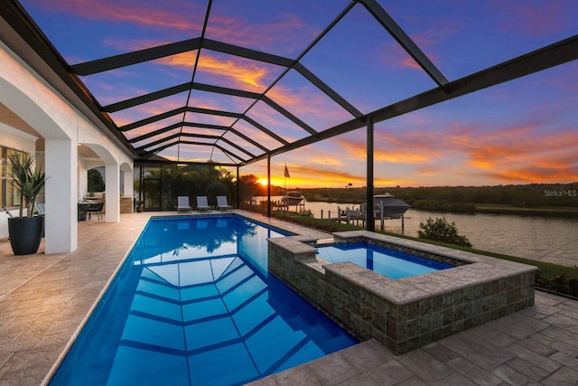 pool at dusk with glass enclosure, an in ground hot tub, a water view, and a patio area