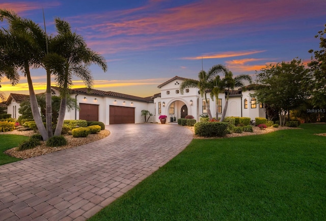 mediterranean / spanish home with a lawn and a garage