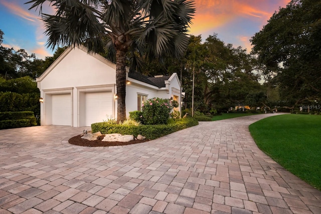 property exterior at dusk with a lawn and a garage