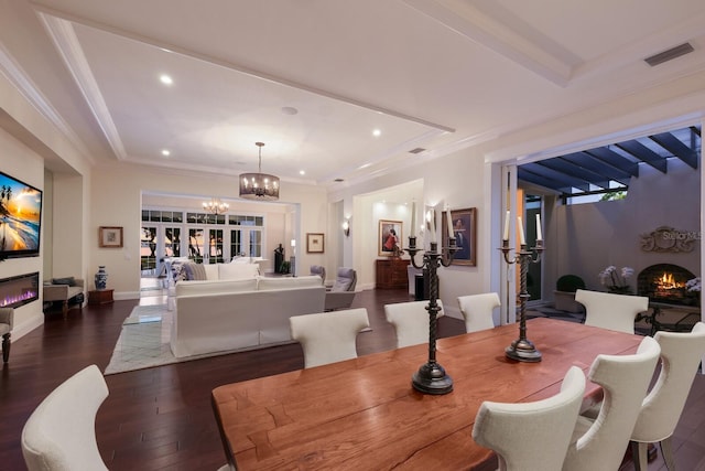 dining space with dark hardwood / wood-style floors, a fireplace, a chandelier, and a tray ceiling