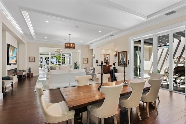 dining room featuring a raised ceiling, crown molding, dark wood-type flooring, and an inviting chandelier