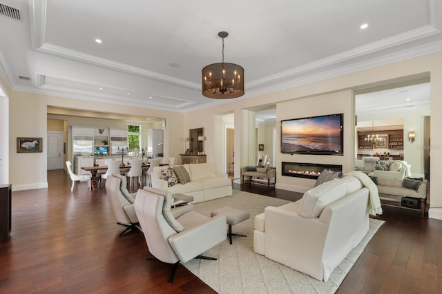 living room featuring crown molding, dark wood-type flooring, and an inviting chandelier