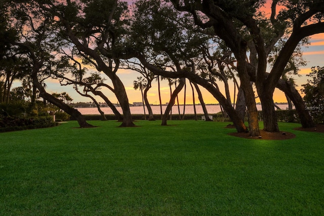 yard at dusk featuring a water view