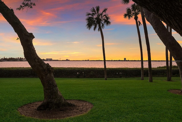 yard at dusk featuring a water view