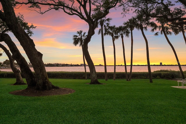 yard at dusk featuring a water view