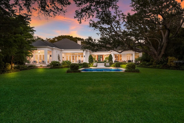 back house at dusk featuring a yard