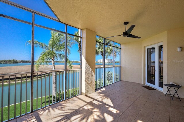 unfurnished sunroom featuring ceiling fan and a water view