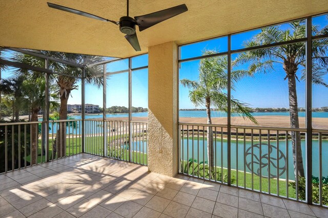 unfurnished sunroom with ceiling fan and a water view