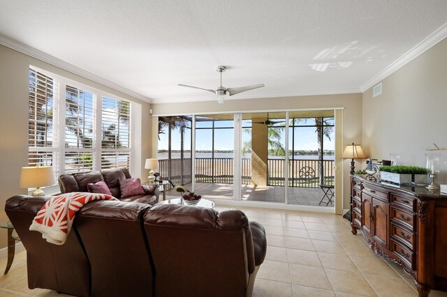 living room featuring a textured ceiling, ceiling fan, light tile floors, and ornamental molding